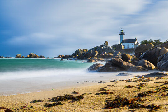 A lighthouse overlooks the sea on a rocky coast in Brittany France