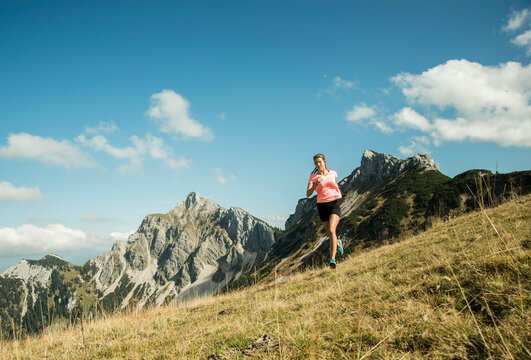 Austria, Tyrol, Tannheim Valley, young woman jogging in mountains