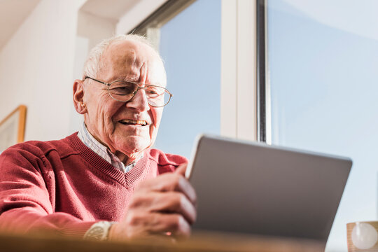 Senior man sitting at home, using laptop
