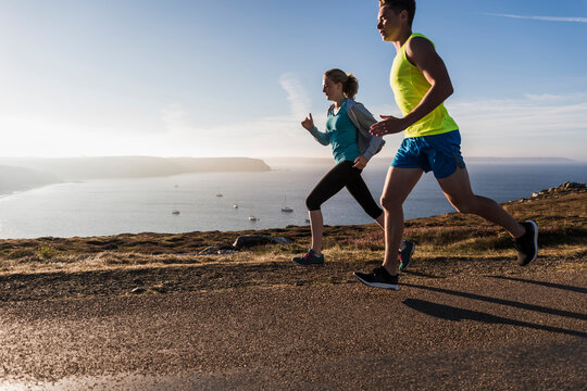 France, Crozon peninsula, young couple running on coastal road