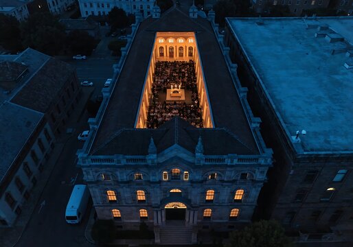 High angle aerial view of a historic stone building illuminated at night with warm lights in the courtyard stone architecture urban architecture old town blue hour historic site