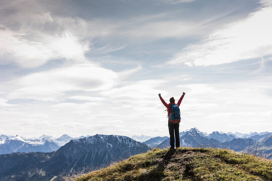 Austria, Tyrol, young woman standing in mountainscape cheering