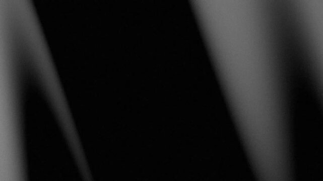 Abstract grainy black and white background with diagonal light and shadow