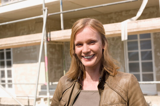 Woman in front of her New House, smiling, portrait