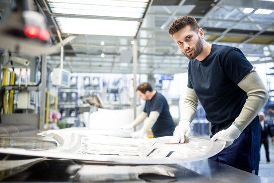 Portrait of worker wiping component in car factory