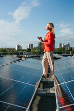 Woman holds digital tablet on roof with solar panel for green energy