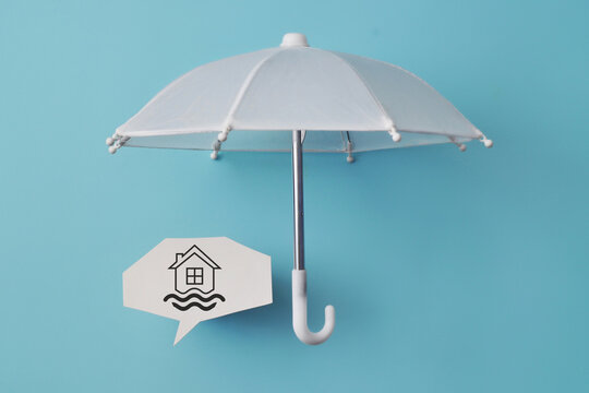 White umbrella protecting a house symbol with water waves, representing home insurance and protection against flooding or water-related property damage.