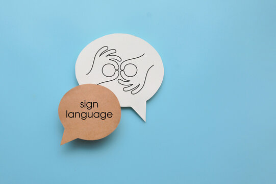 Two speech bubbles displaying hand gesture symbols associated with sign language, emphasizing nonverbal communication and visual language.