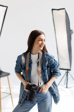 Young woman photographer taking photo, lady working at studio, using professional dslr camera