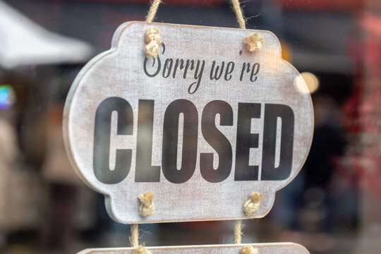 Sorry we are closed sign hanging on a shop glass window