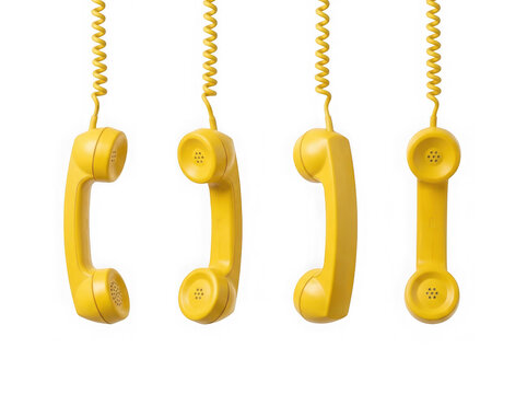 Four yellow vintage telephone handsets hanging isolated on white background