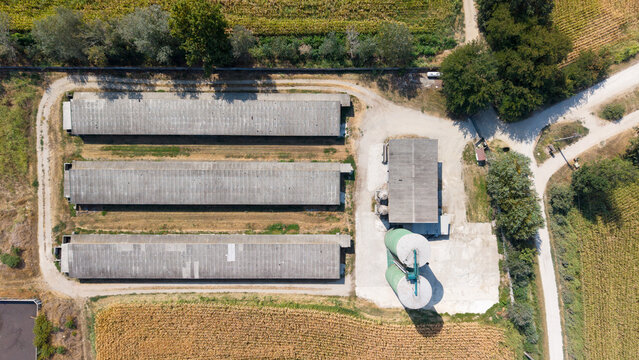 Aerial view of a grain storage facility with three long barns and two silos on an Italian farm in Mediglia, Lombardy, Italy.
