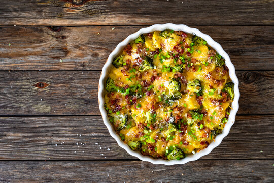 Potato broccoli casserole - baked potatoes with broccoli, cheddar cheese and smoked bacon on wooden table. Top view

