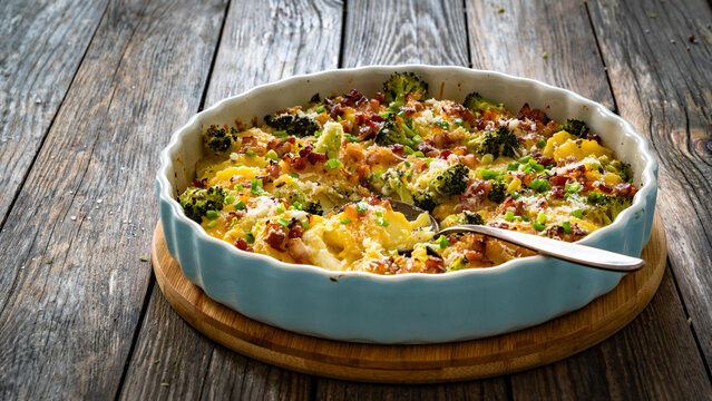 Potato broccoli casserole - baked potatoes with broccoli, cheddar cheese and smoked bacon on wooden table
