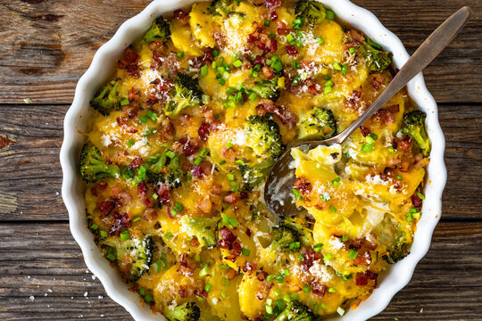 Potato broccoli casserole - baked potatoes with broccoli, cheddar cheese and smoked bacon on wooden table. Top view

