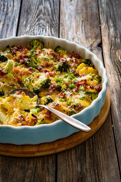 Potato broccoli casserole - baked potatoes with broccoli, cheddar cheese and smoked bacon on wooden table
