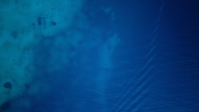 Aerial view of turquoise shallow waters transitioning into deep blue sea near the coast of Rab, Primorje-Gorski Kotar, Croatia.