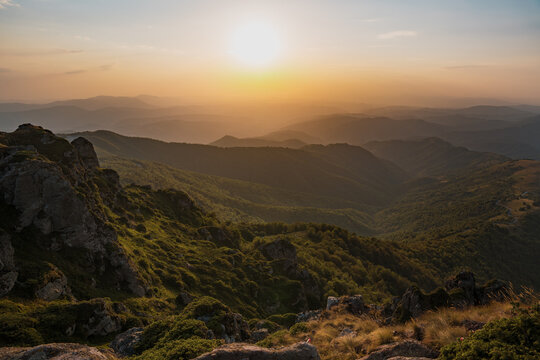 Golden hour sunset light over the rocky peaks and green slopes of Babin Zub with distant mountain layers in the background at Stara Planina reserve in Serbia.