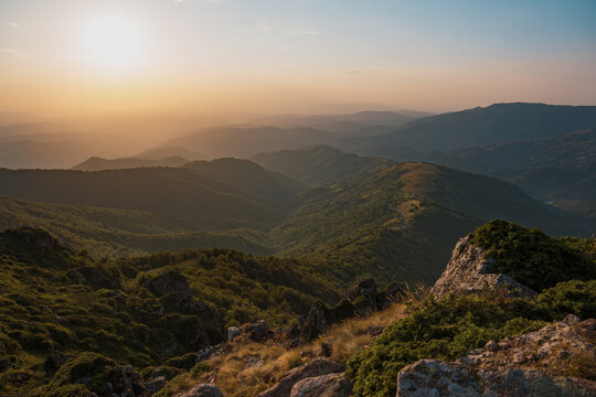 Golden hour sunset light over the rocky peaks and green slopes of Babin Zub with distant mountain layers in the background at Stara Planina reserve in Serbia.