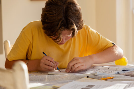 13 year old boy doing geometry homework in light filled room