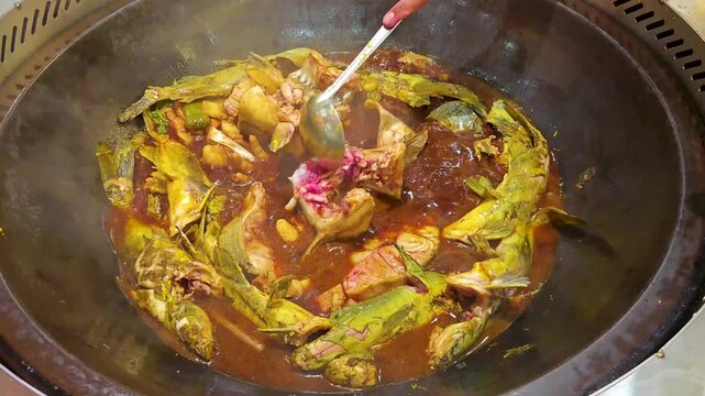 Hand Stirring Whole Fish Stew in Large Pot