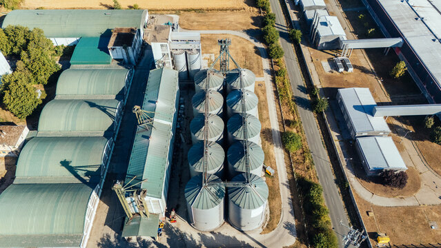 Aerial view of industrial grain silos and storage facility with metal roofs and surrounding infrastructure in Indjija, Vojvodina, Serbia.