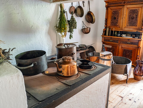 Vintage Rural Kitchen Interior With Antique Copper Kettle, Pots and Hanging Herbs on Wood Stove