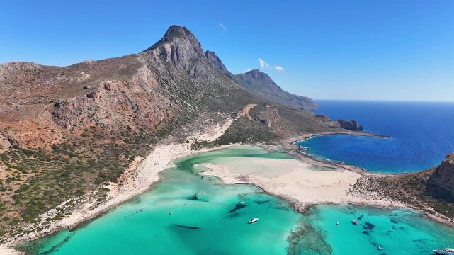 Balos Lagoon and Geroskinos Mountain dominate turquoise waters beneath the Gramvousa Peninsula, Kissamos, Chania, Crete, Greece, drone forward flyover.