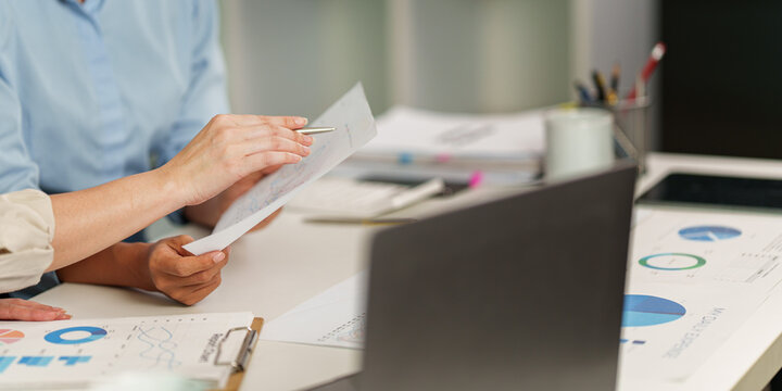 Cropped view of business team analyzing financial report documents on office desk