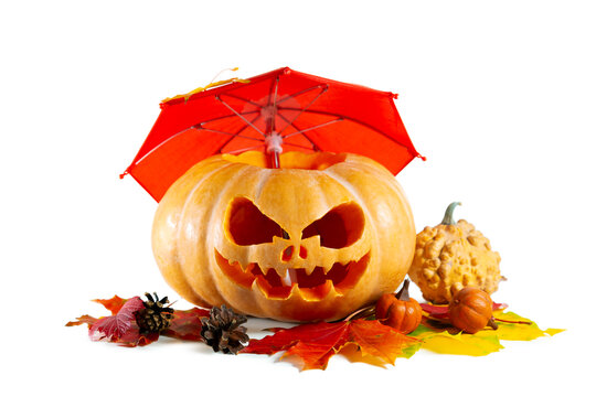 Halloween pumpkin with scary face, red umbrella and autumn leaves isolated on white.