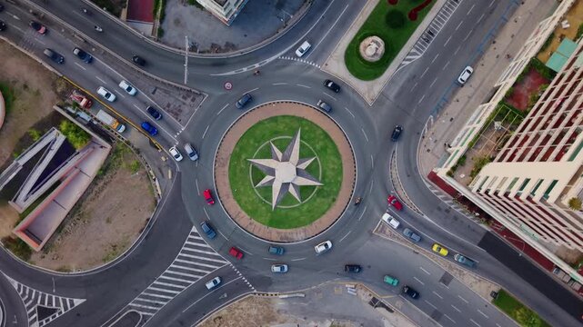Aerial view of busy roundabout with cars and compass rose in Genoa city center