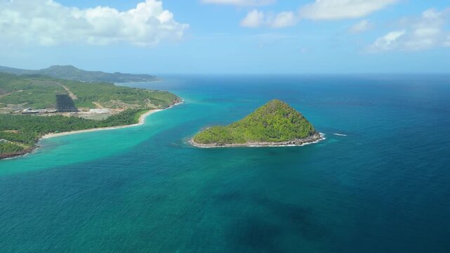 Sugar Loaf Island Grenada forms green peak surrounded by turquoise water off rugged coastline with sandy beach nearby