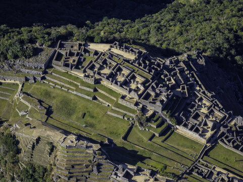 Aerial view of the Historic Sanctuary of Machu Picchu featuring ancient stone ruins and agricultural terraces set amidst lush green mountains in Urubamba Province, Cusco, Peru.