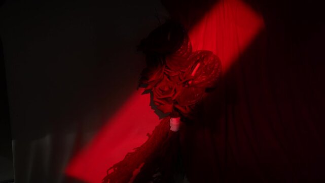 Moody close-up of rose bouquet illuminated by sweeping red spotlight across draped fabric, with rose, bouquet, spotlight, red detail, showing shadow, contrast, petal, fabric 