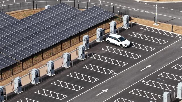 Aerial view of a modern electric car parking at a charging station powered by solar panels, showcasing sustainable transport, renewable energy, and future of clean mobility infrastructure