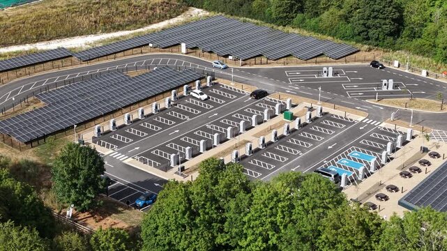 High angle drone footage of a modern electric car charging station with solar panel canopies generating renewable energy for sustainable transportation and future e mobility infrastructure