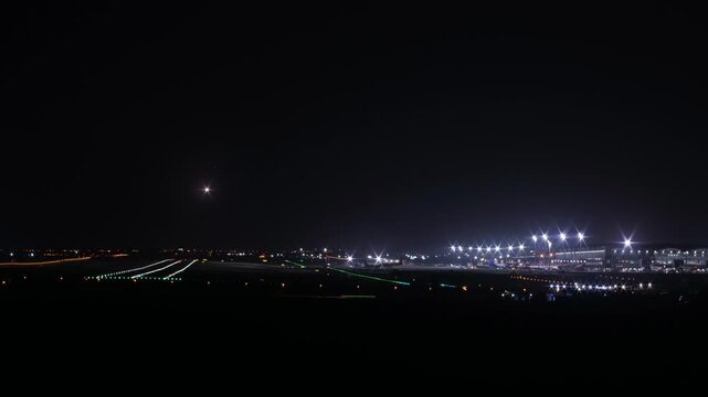 Cinematic night timelapse of airplanes landing head-on at an airport. Dynamic runway traffic, glowing lights. Alicante Airport, Spain.