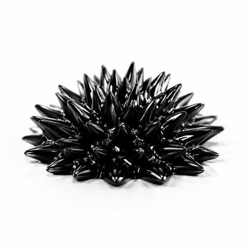 Ferrofluid forming black spikes above a magnet on a white surface