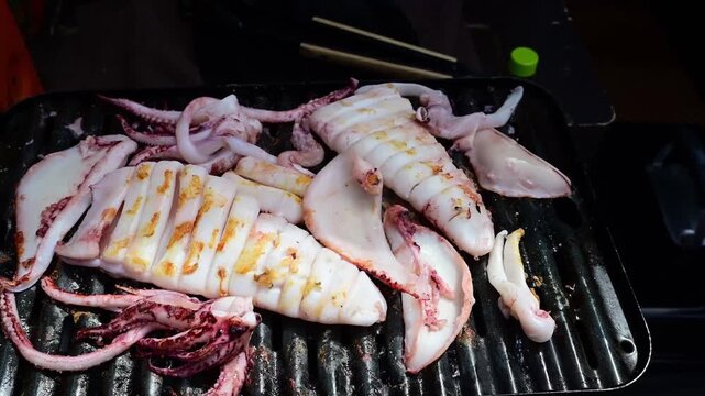 Grilled squid sizzling on an electric barbecue griddle