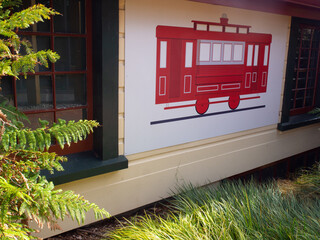 Red vintage cable car mural on outdoor building wall © mcgimpseymike