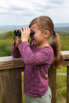 Girl exploring nature while using binoculars in a scenic landscape