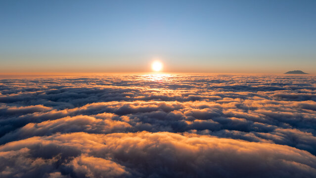 Aerial view of the sunrise over a vast sea of clouds near Mount Telomoyo in Kecamatan Ngablak, Jawa Tengah, Indonesia.