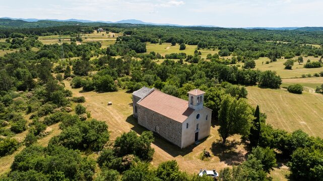 Aerial view of the historic stone church in Sterna surrounded by lush green trees and rolling fields in the rural landscape of Sterna, Istarska zupanija, Croatia.