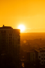 Naklejka premium A beautiful sunset and sunny rain. Orange and amber hues of a beautiful sunset against a backdrop of fog and light rain on a summer evening. Golden hour.