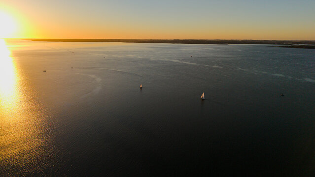 Aerial view of the Parana River at sunset with sailboats gliding across the calm water in Posadas, Misiones Province, Argentina.
