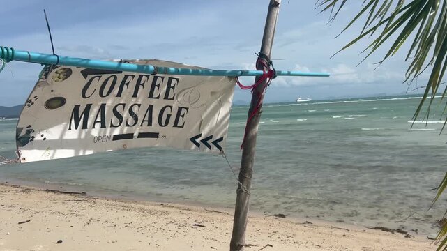 Coffee massage sign near the beach shows open service for visitors seeking relaxation by the water