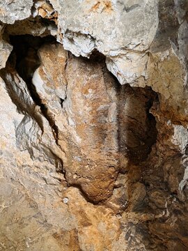 Natural cave formation showing rough limestone rock texture in golden and beige shades