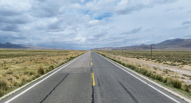 Long Straight Highway Stretching Across Arid Plateau Landscape
