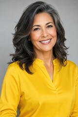 Fototapeta premium Woman with grey streaked hair in a yellow blouse in studio light