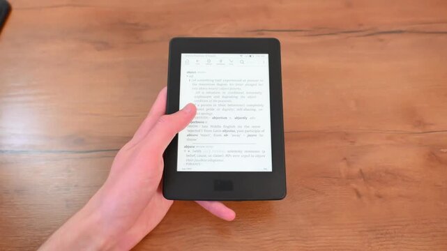 Quiet focus while holding digital reader on natural wooden table